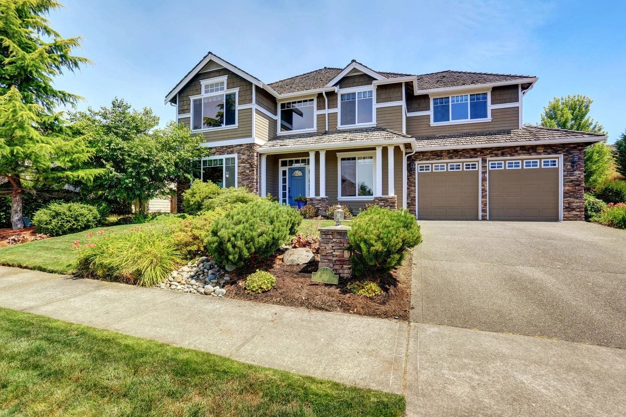 A large house with a driveway and bushes.