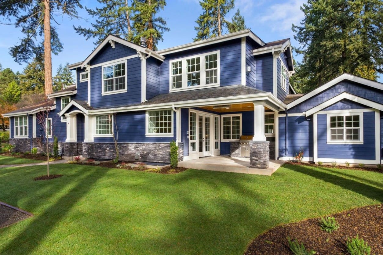 A blue house with white trim and green grass.